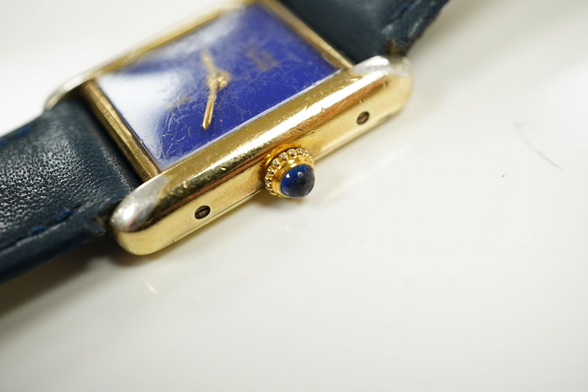 A lady's gilt 925 Must De Cartier manual wind wrist watch, with lapis lazuli rectangular dial and cabochon sapphire set winding crown, on an associated leather strap, case diameter 20mm, no box or papers. Condition - poo